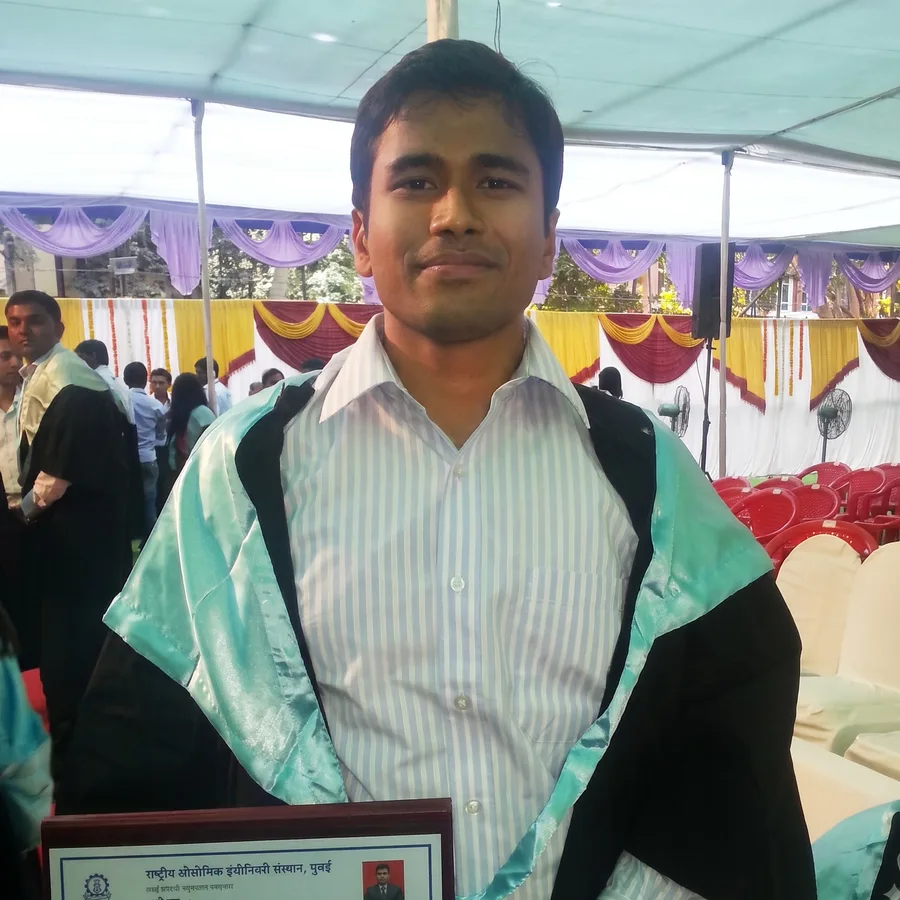 Lavi at his convocation in a black gown and teal stole, holding his degree certificate.