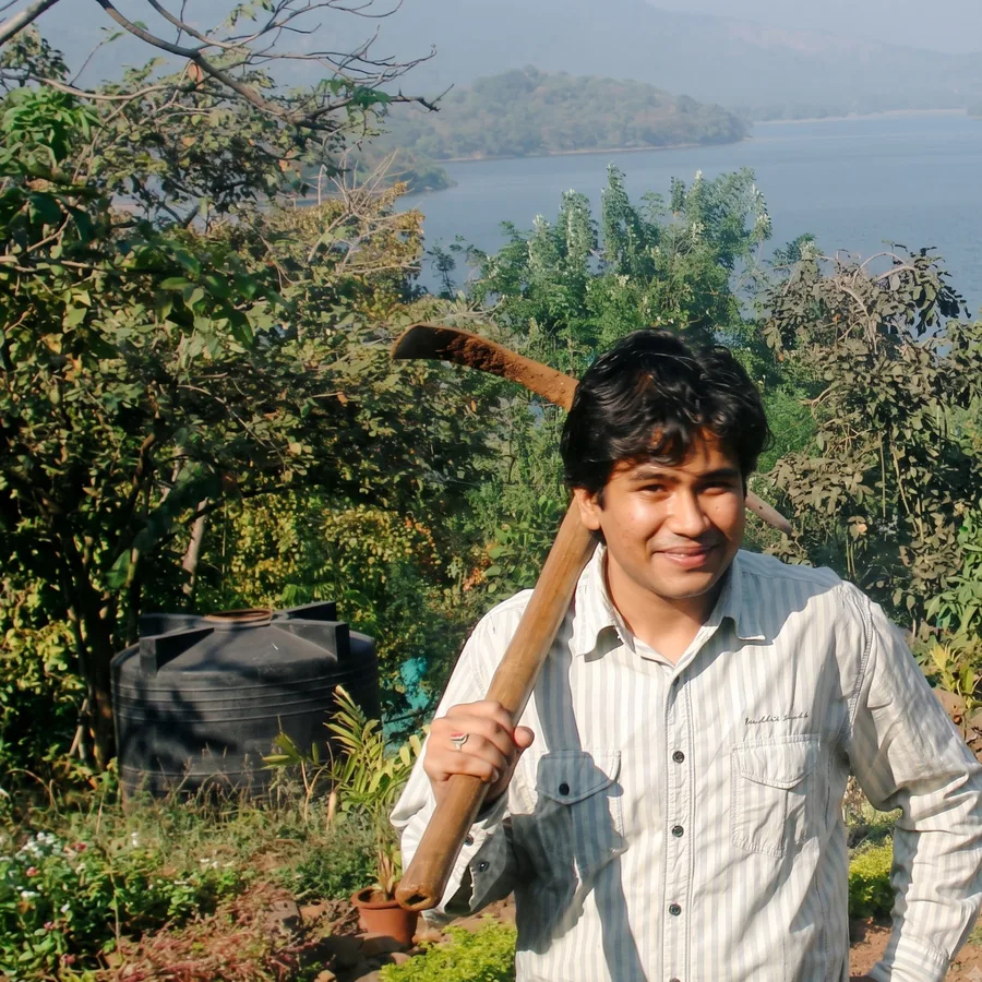 Lavi with a pickaxe on his shoulder in a garden above a lake