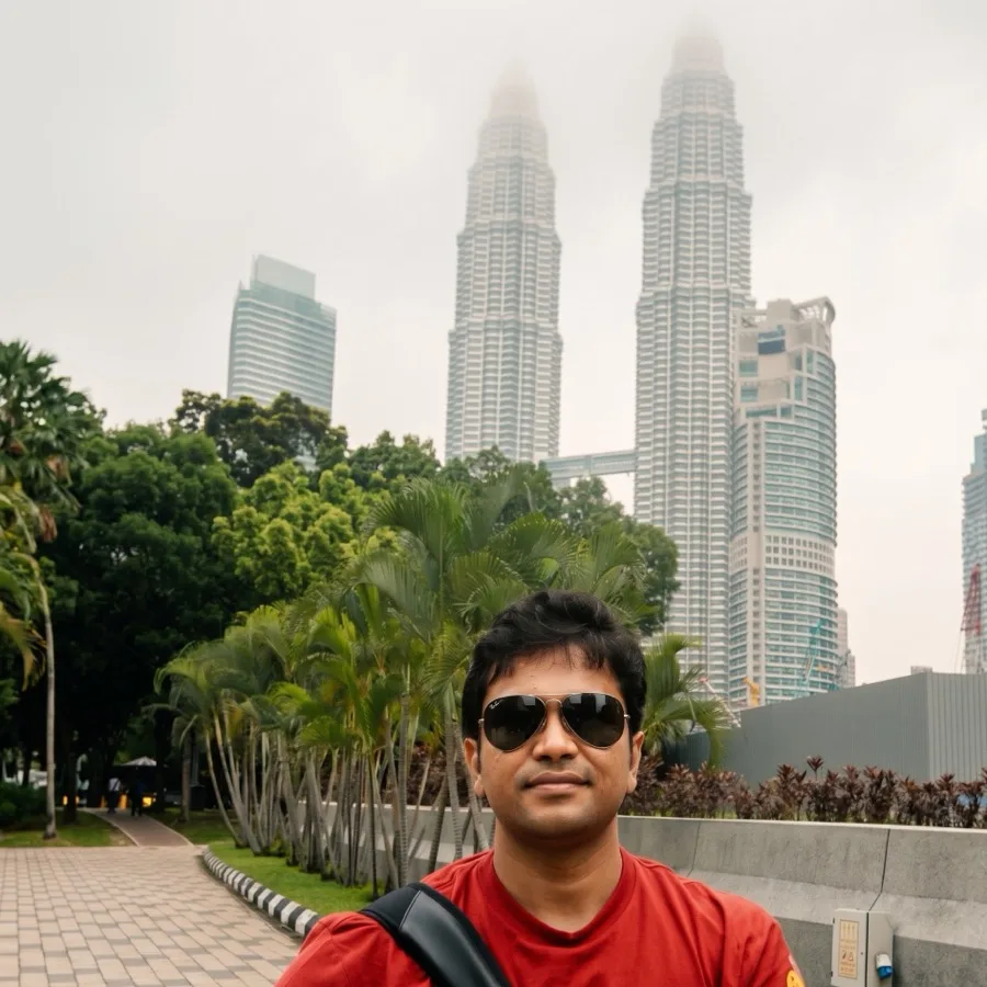 Lavi takes a selfie in sunglasses with the Petronas Towers behind him.