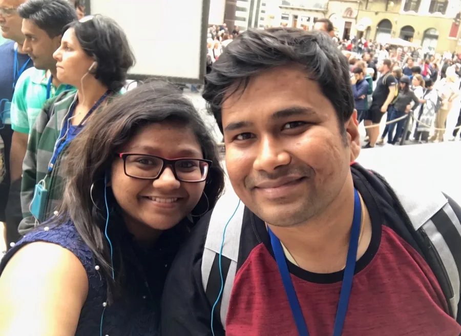 Lavi and a woman smile in a close selfie in a busy crowd.