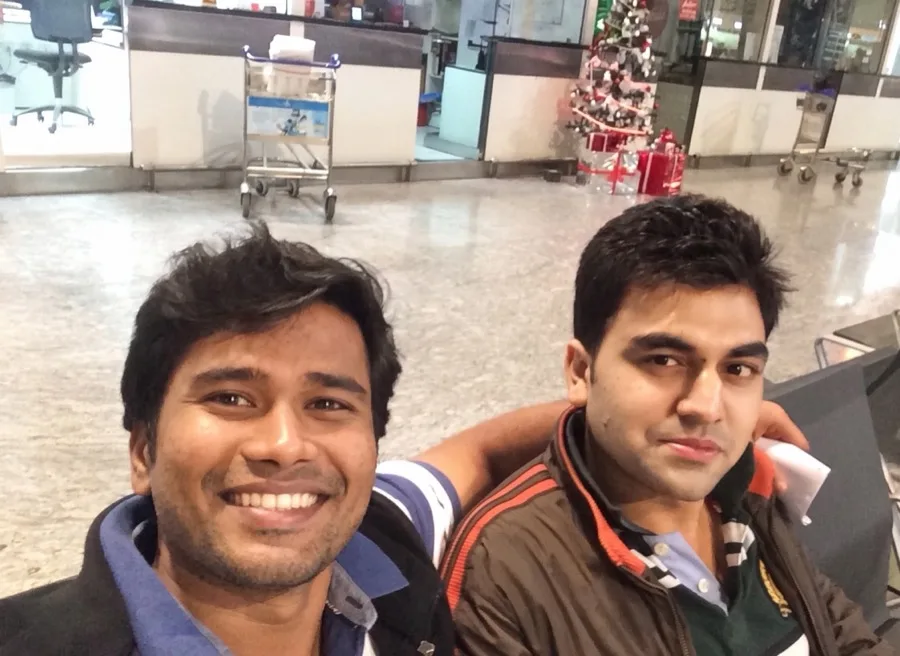 Lavi takes a smiling selfie with a friend in an airport terminal.