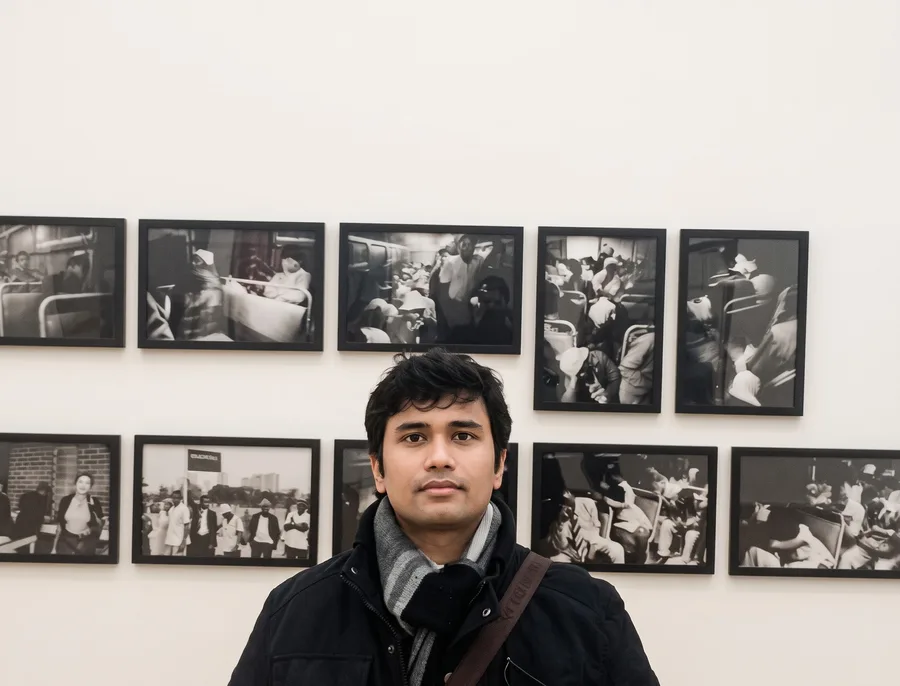 Lavi stands below a wall of framed black and white photographs.