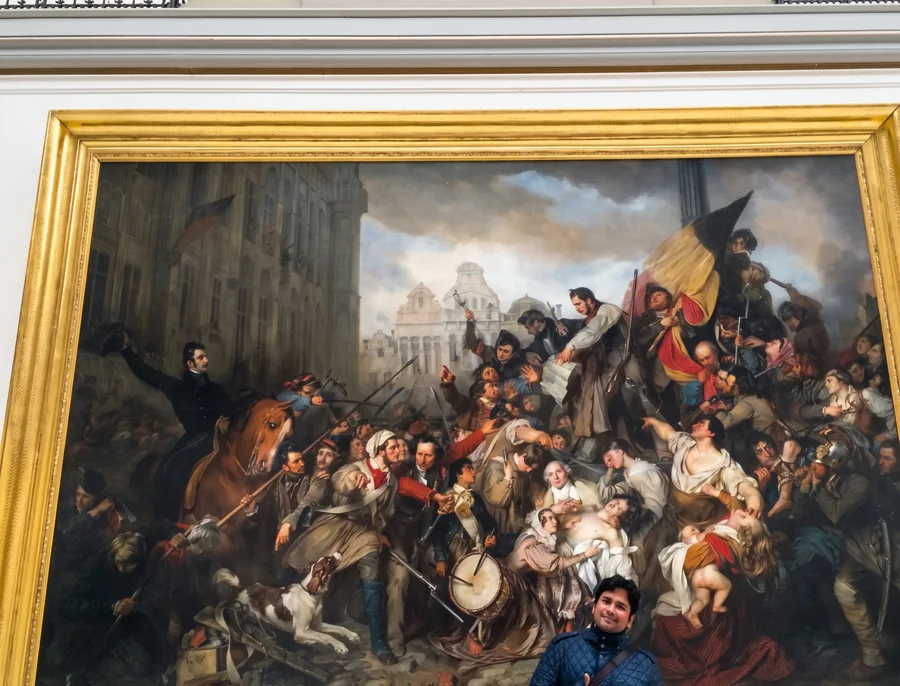 Lavi sits small beneath a huge gilded painting in a museum.